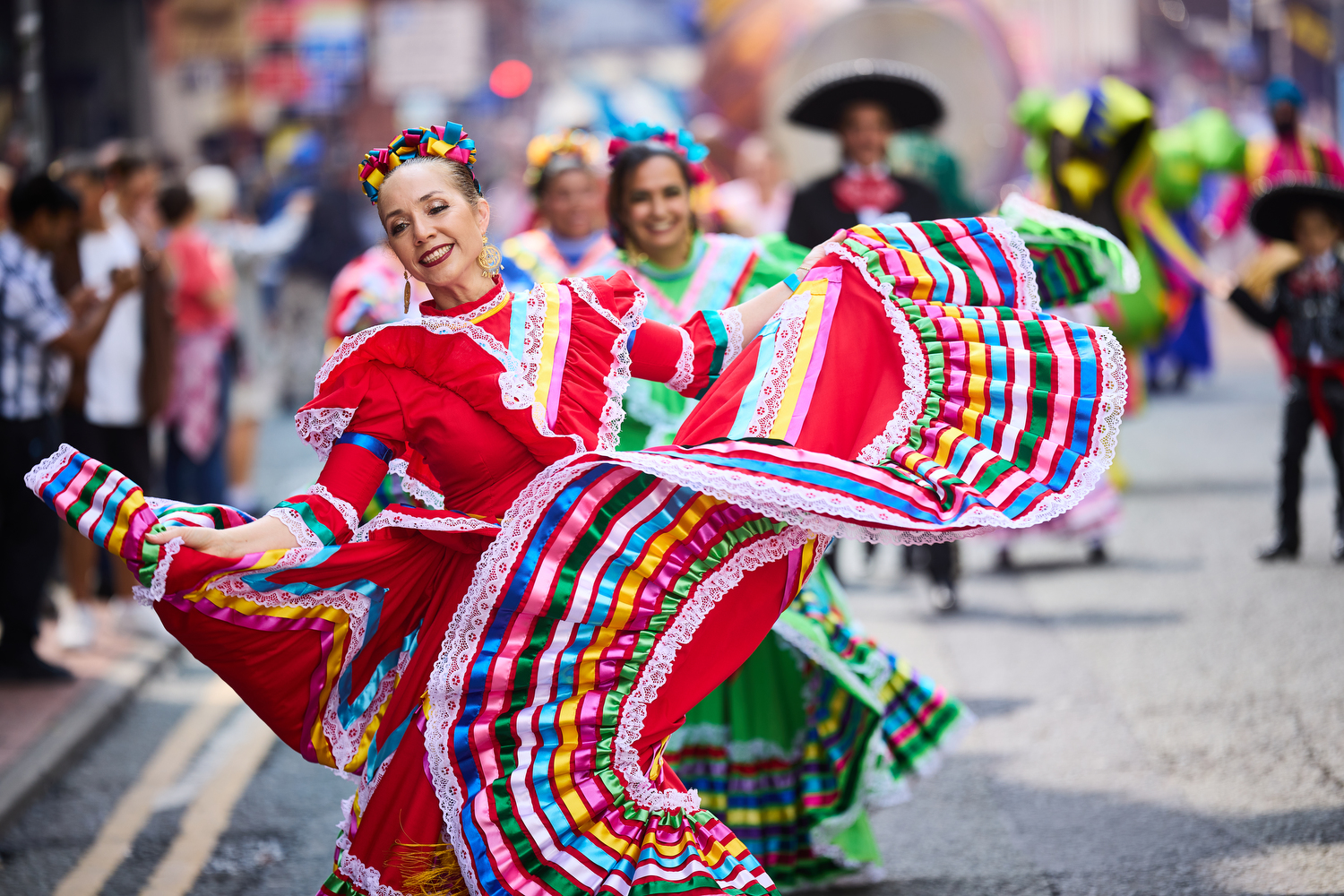 Street scene. Dancers wearing brightly coloured Mexican traditional dresses, swirling their skirts around, smiling.