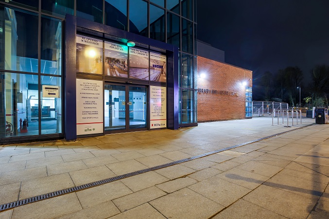 A photo of Hulme High Street library's main entrance at night.