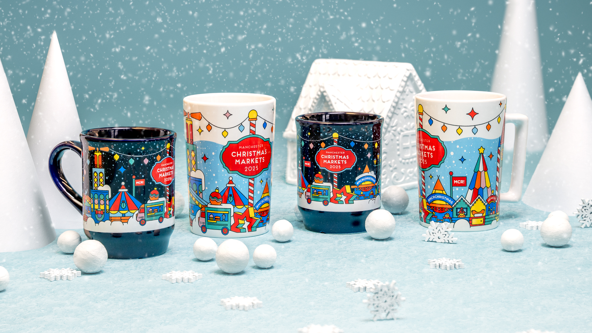 Four Christmas mugs showing off the two designs for 2025. One is dark and the other is white. Both show stylised market stalls, buildings and a small van against a snowy backdrop.