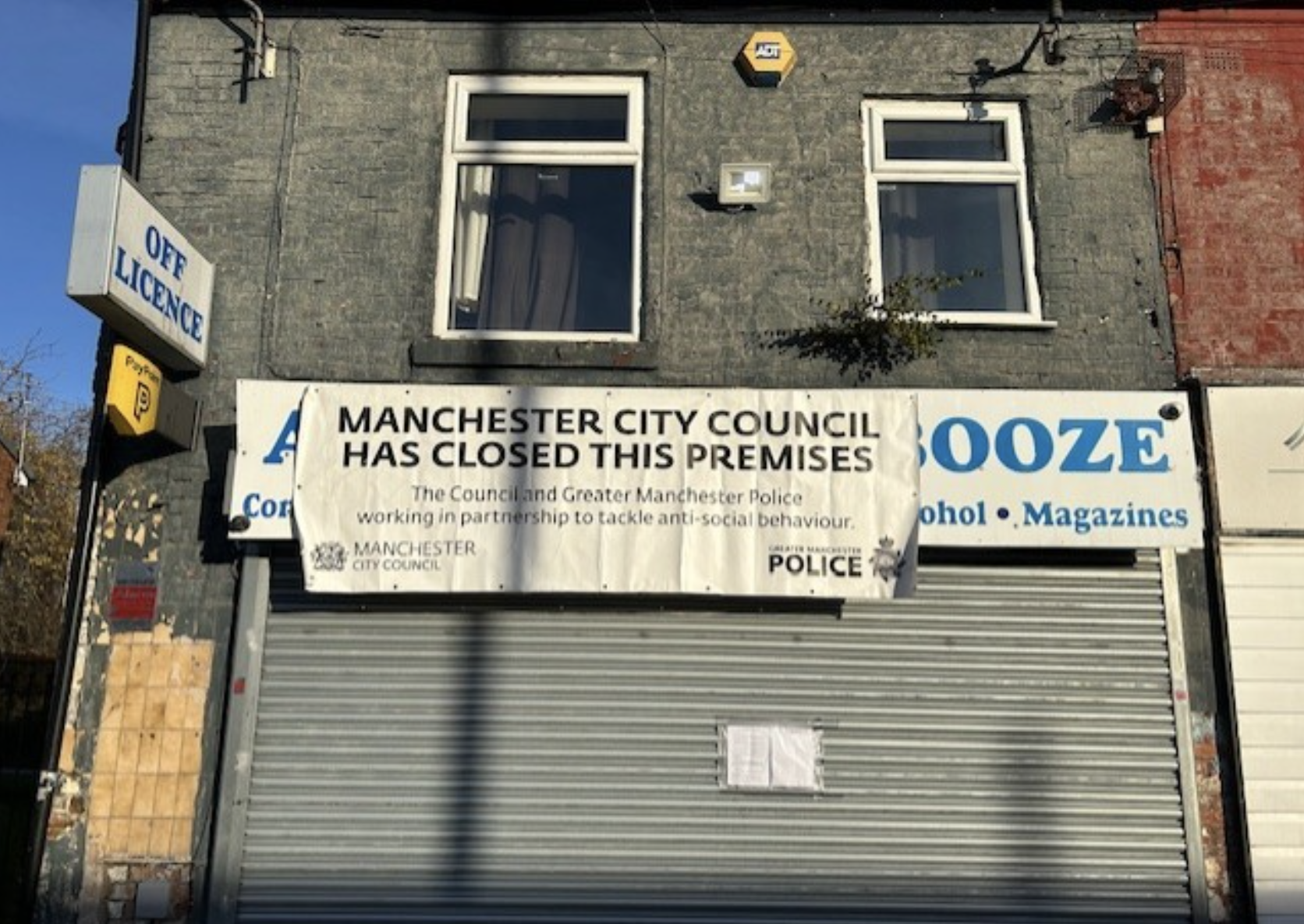 Picture of a shop with a white banner hanging over its front sign. The banner reads "Manchester City Council has closed these premises."