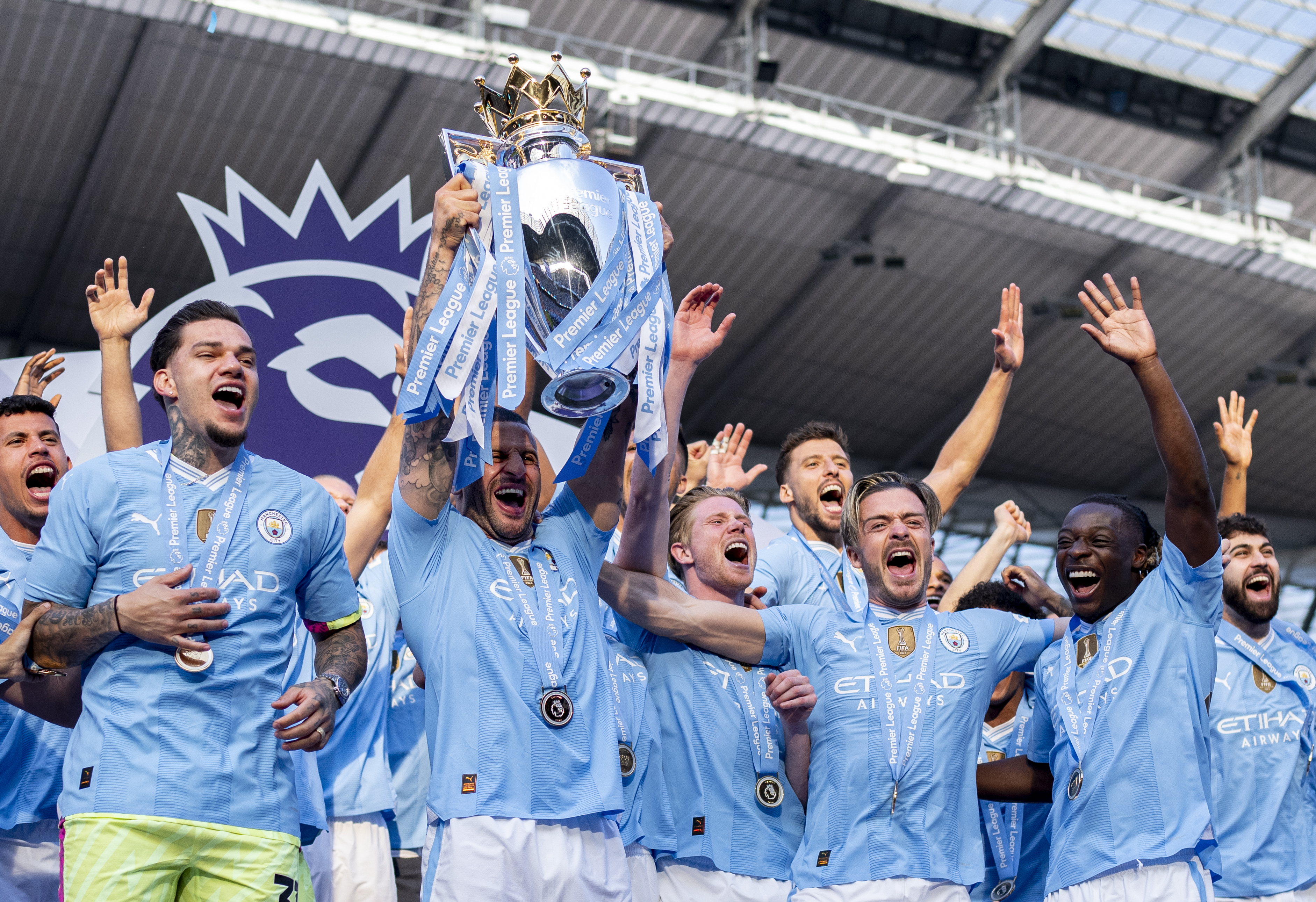Cheering footballers dressed in their blue kit raise the winners silver trophy