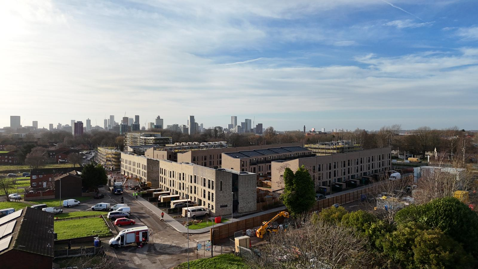drone image looking across new housing in Collyhurst, with city centre in the background