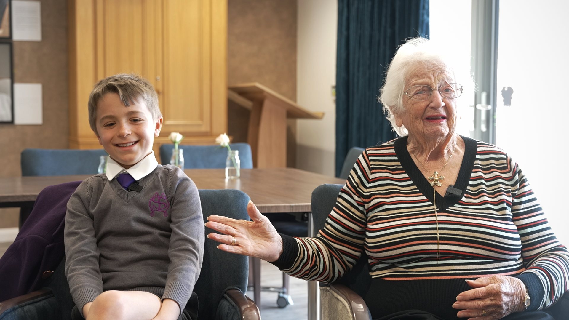 A young boy sits next to an older woman - both smiling