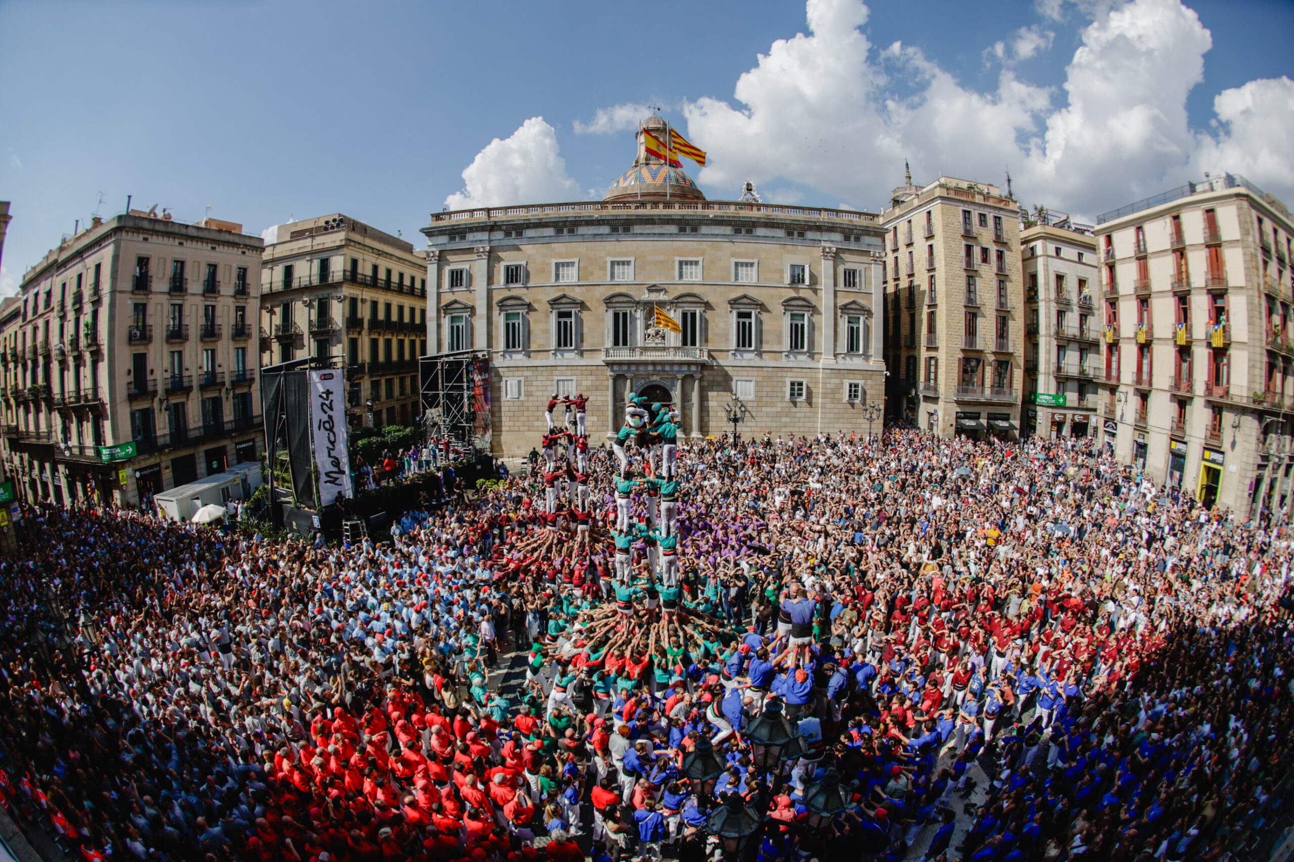 Crowds of people pictured in a town square with buildings around and blue sky Crowds of people pictured in a town square with buildings around and blue sky