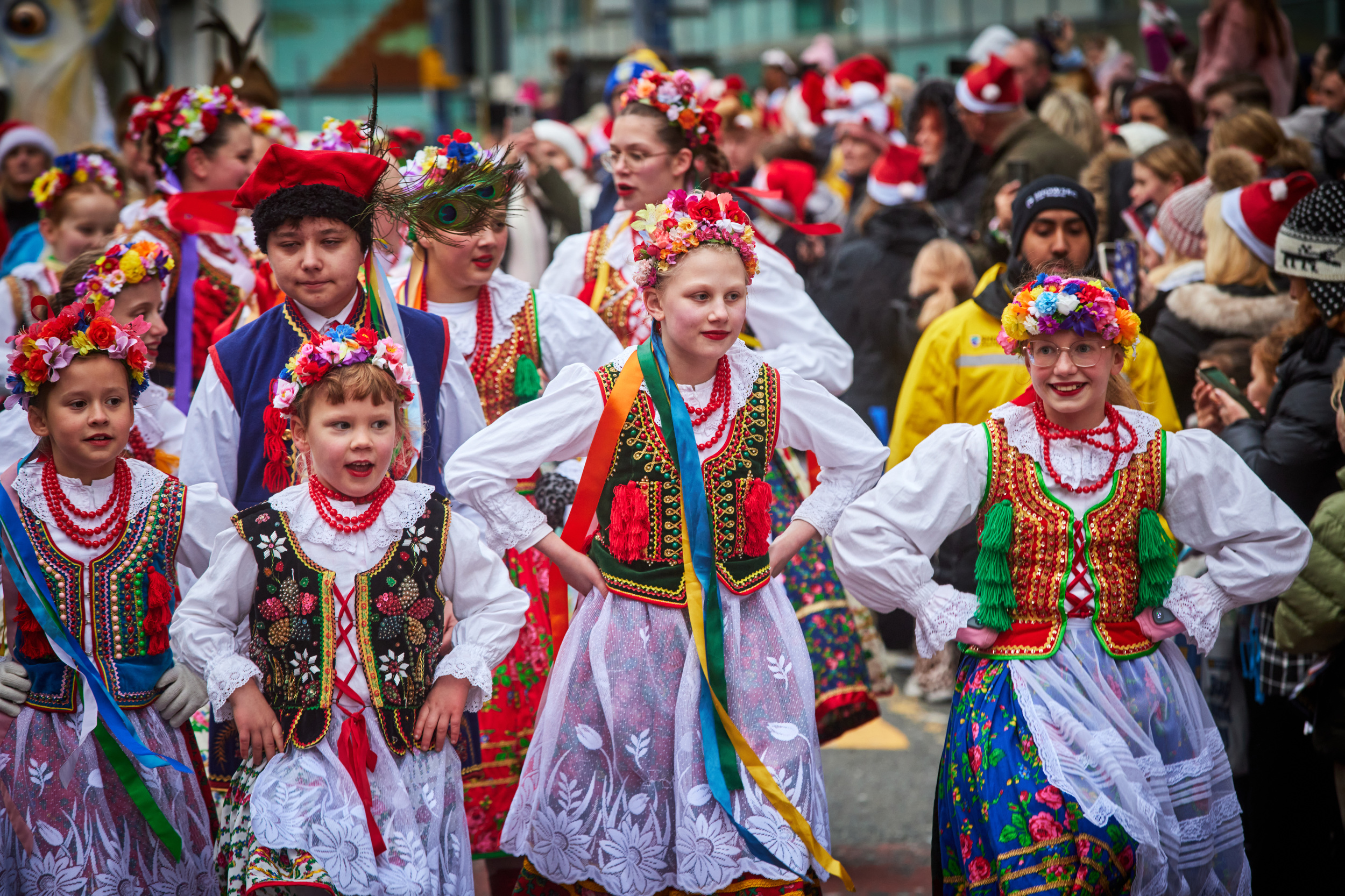 A troupe of young dancers wearing brightly coloured traditional dress, dancing in the street