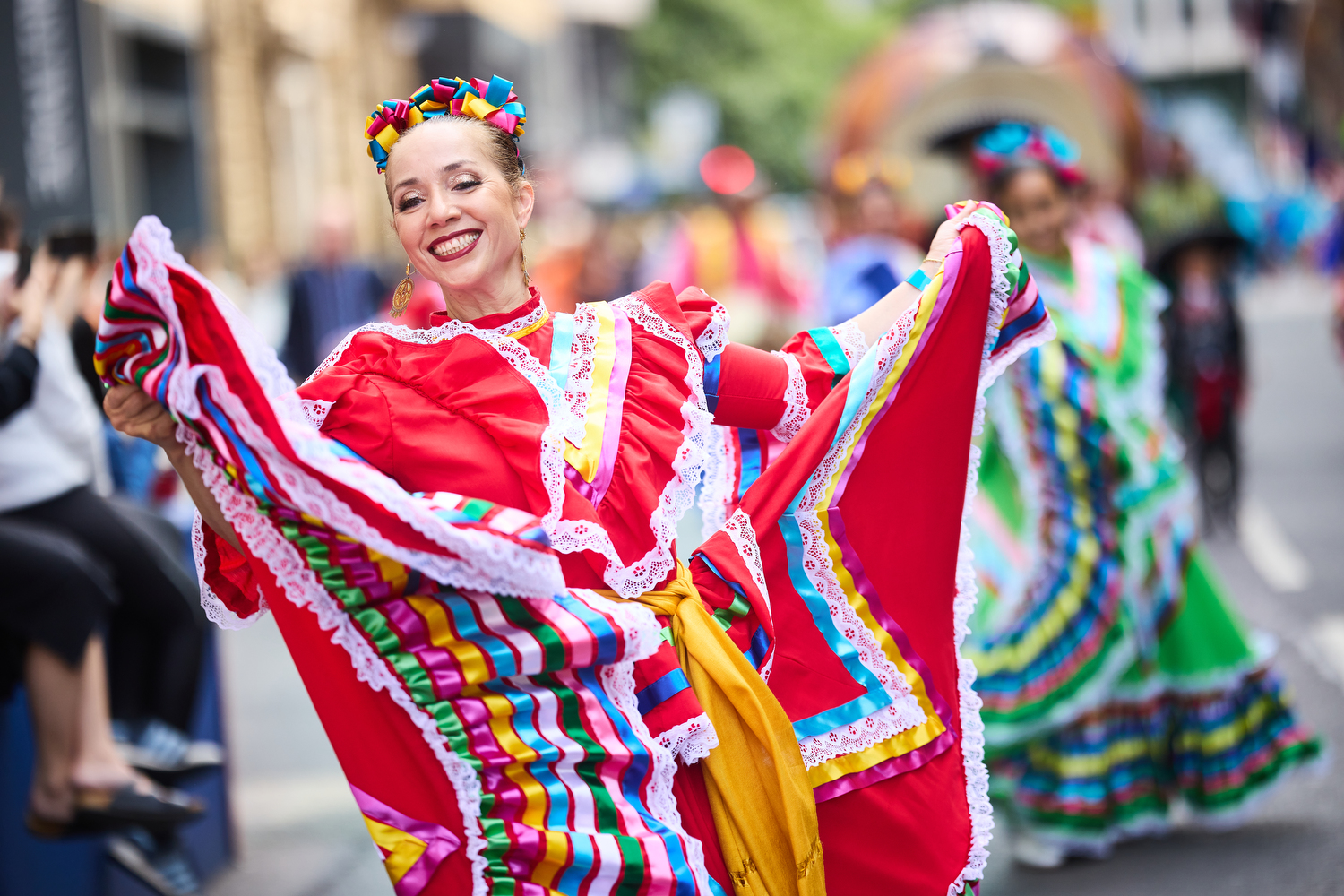 Woman wearing colourful dress dancing in the street smiling
