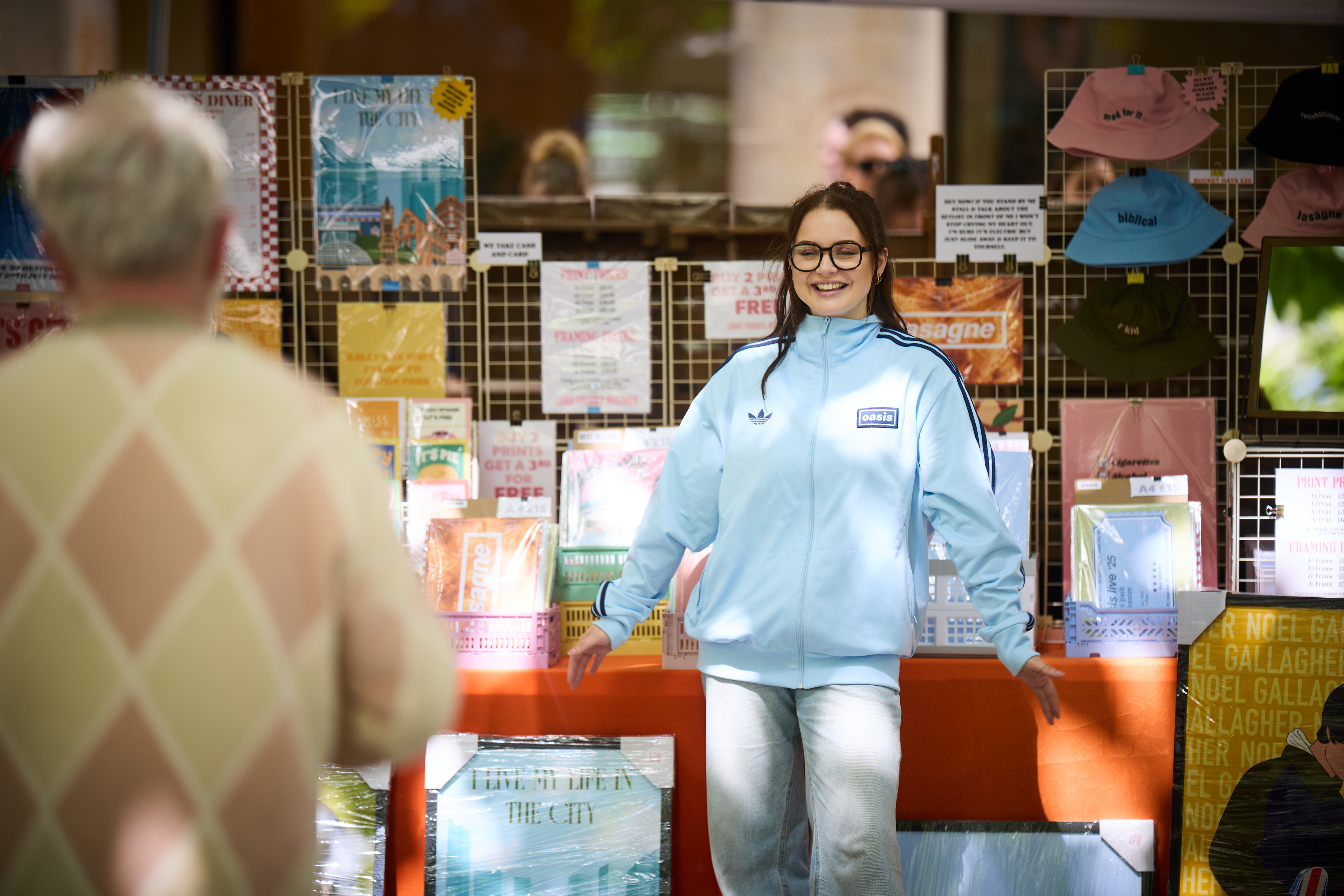 Young woman smiling at the camera as she stands in front of a market stall