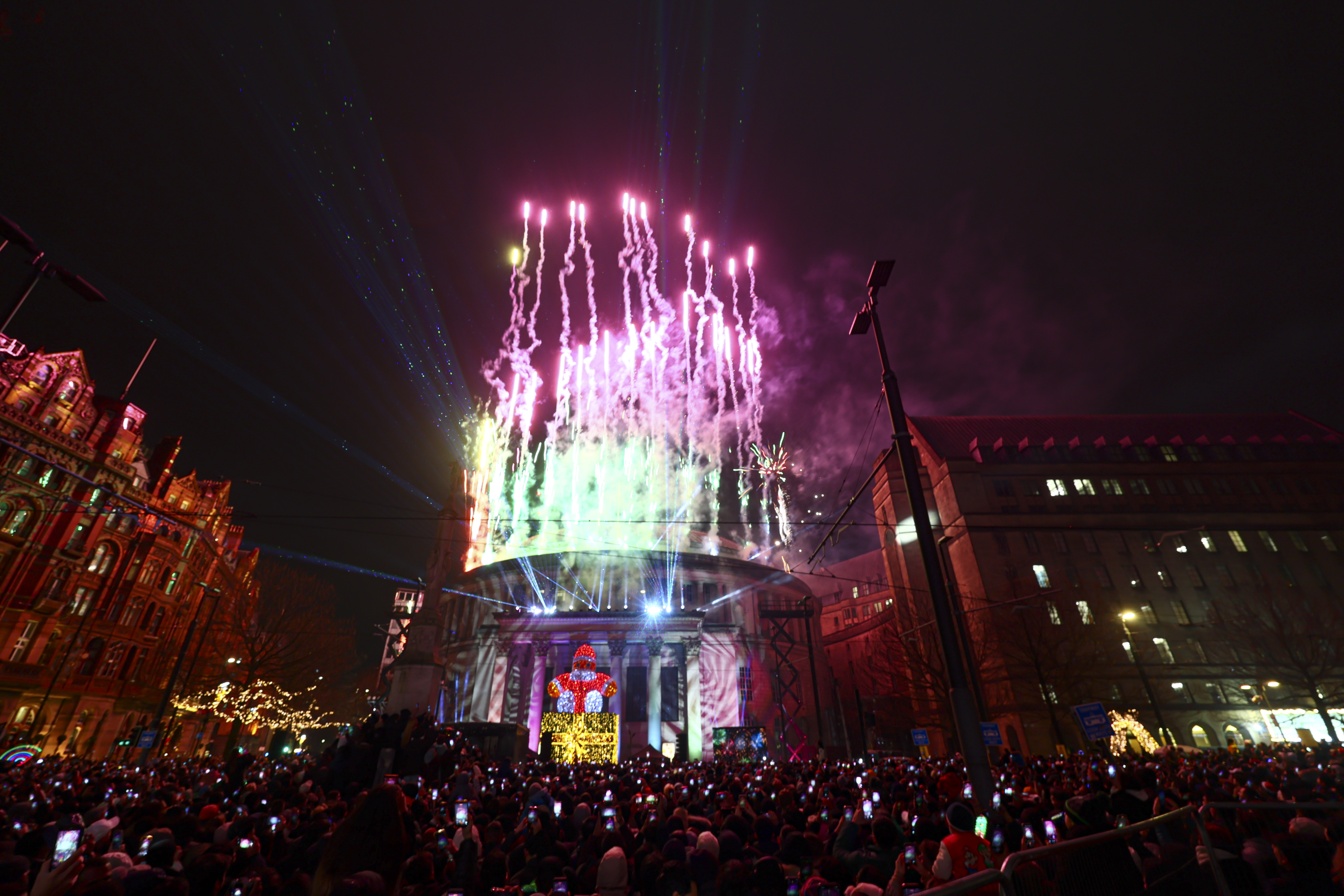 Manchester's Central Library at night lit up with pink fireworks spiralling skywards from its roof