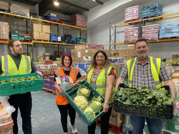 Members of the Rafiki project stood in a warehouse holding pallets of food.