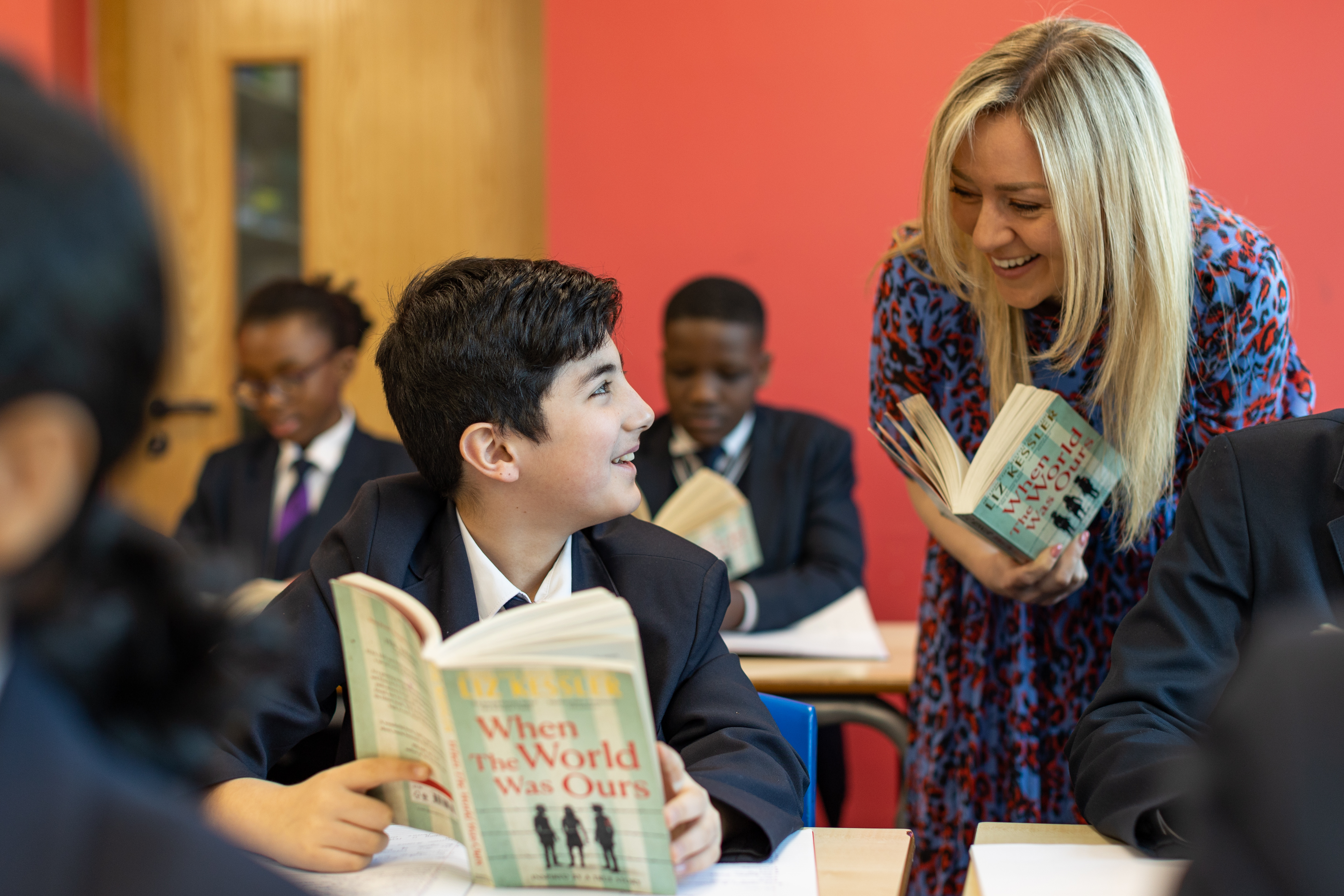 Photo of teacher and pupil discussing a book they are holding.