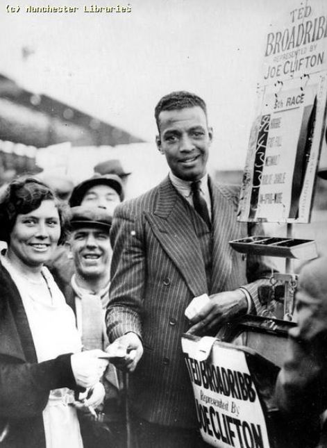 Boxer Len Johnson stand among a crowd of supporters. Black and white archive image.