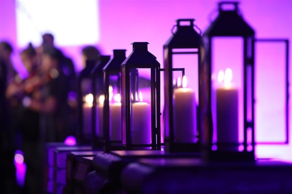 A row of candles against a dim purple light