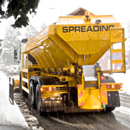 Image of a yellow gritter spreading salt on a road.