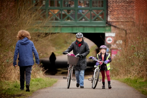 People walking along the Fallowfield Loop with a bicycle between them.