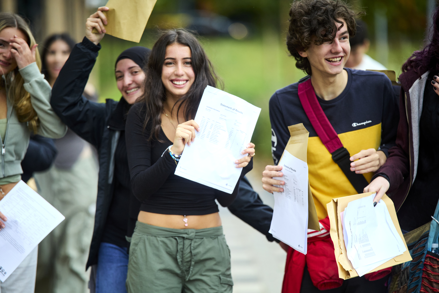 A group of young people smiling and holding envelopes in their hands