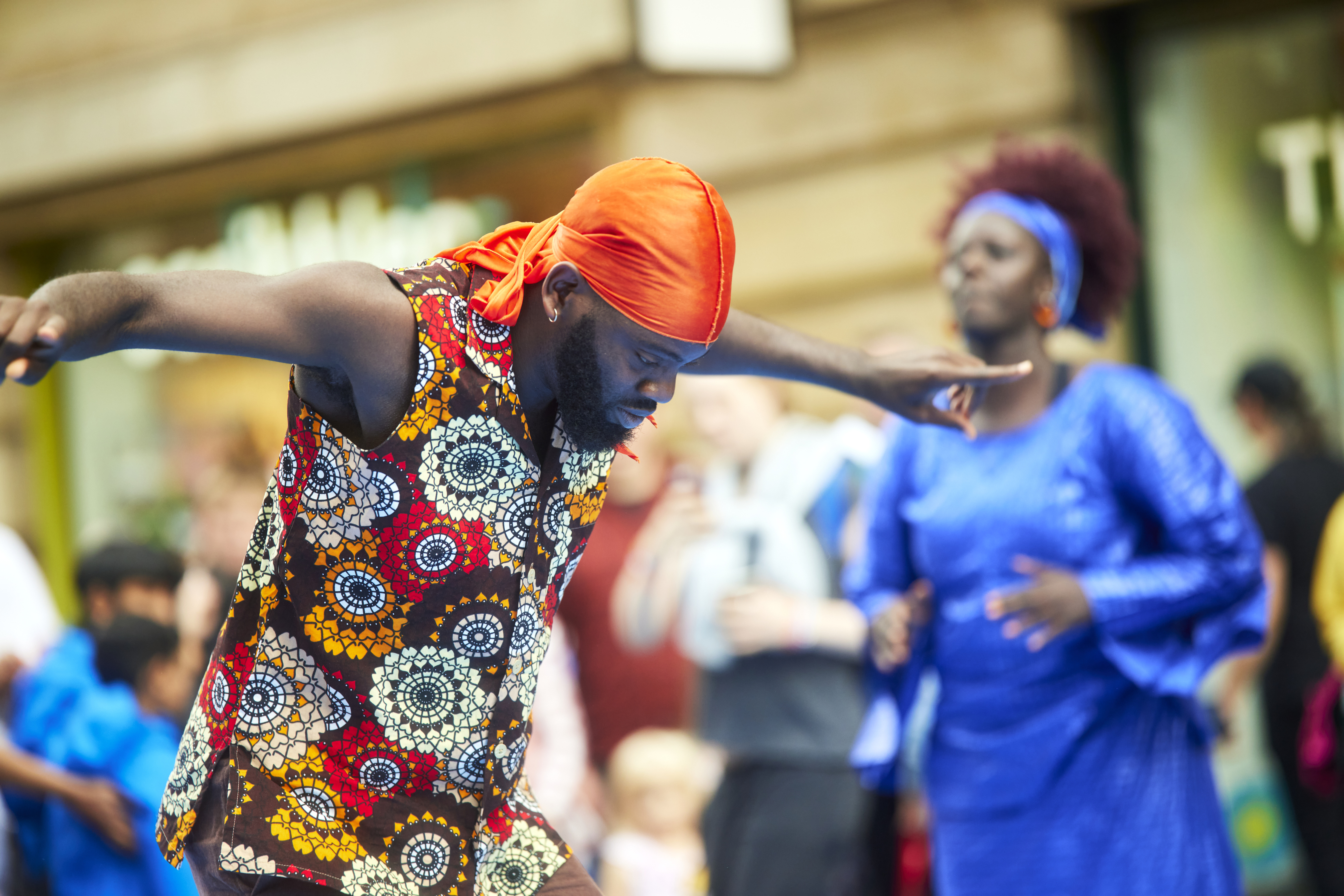 Street scene man dancing wearing bright carnival style clothing