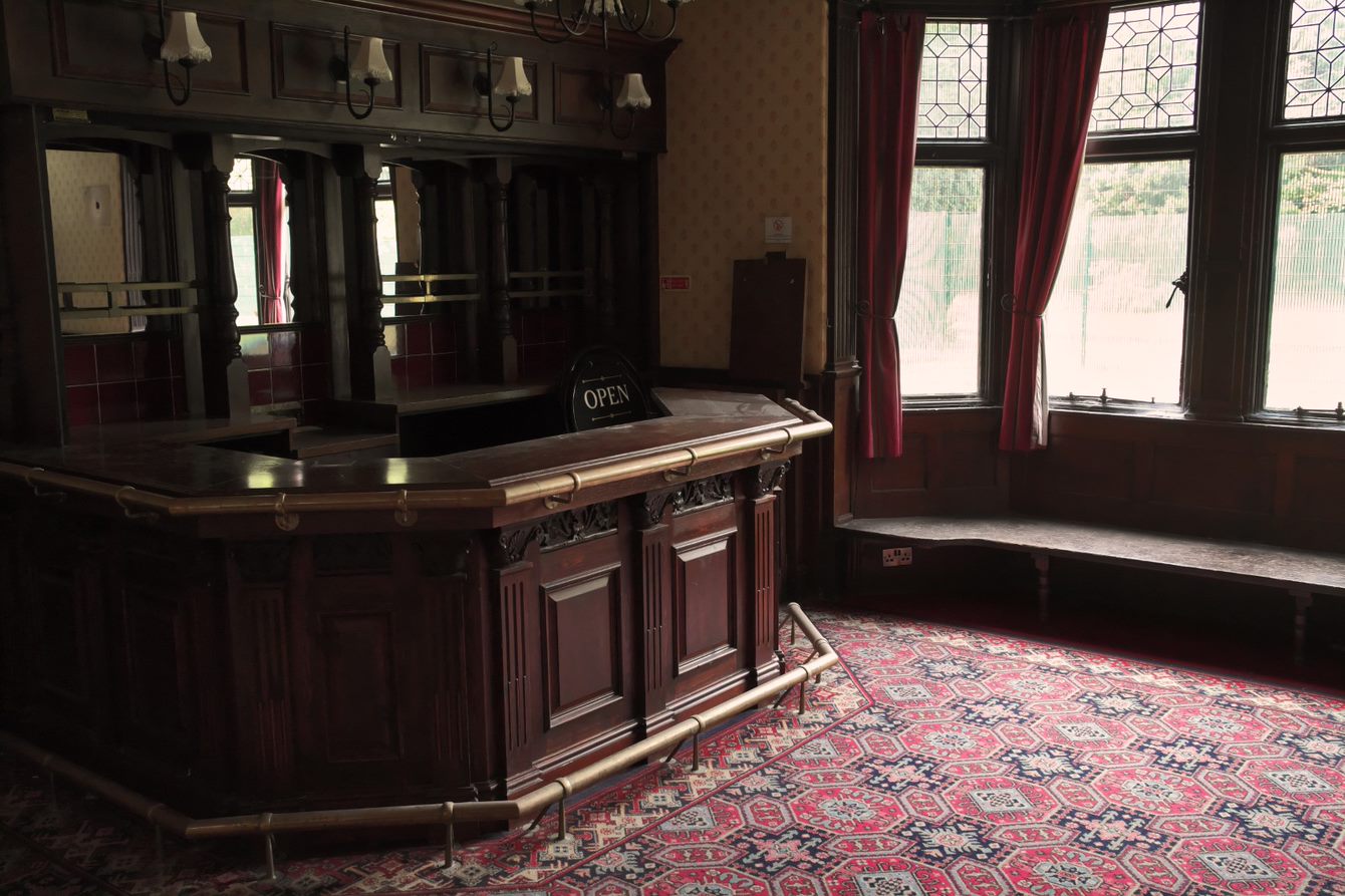 The interior of Wythenshawe Hall, showing a bar, window and patterned carpet 