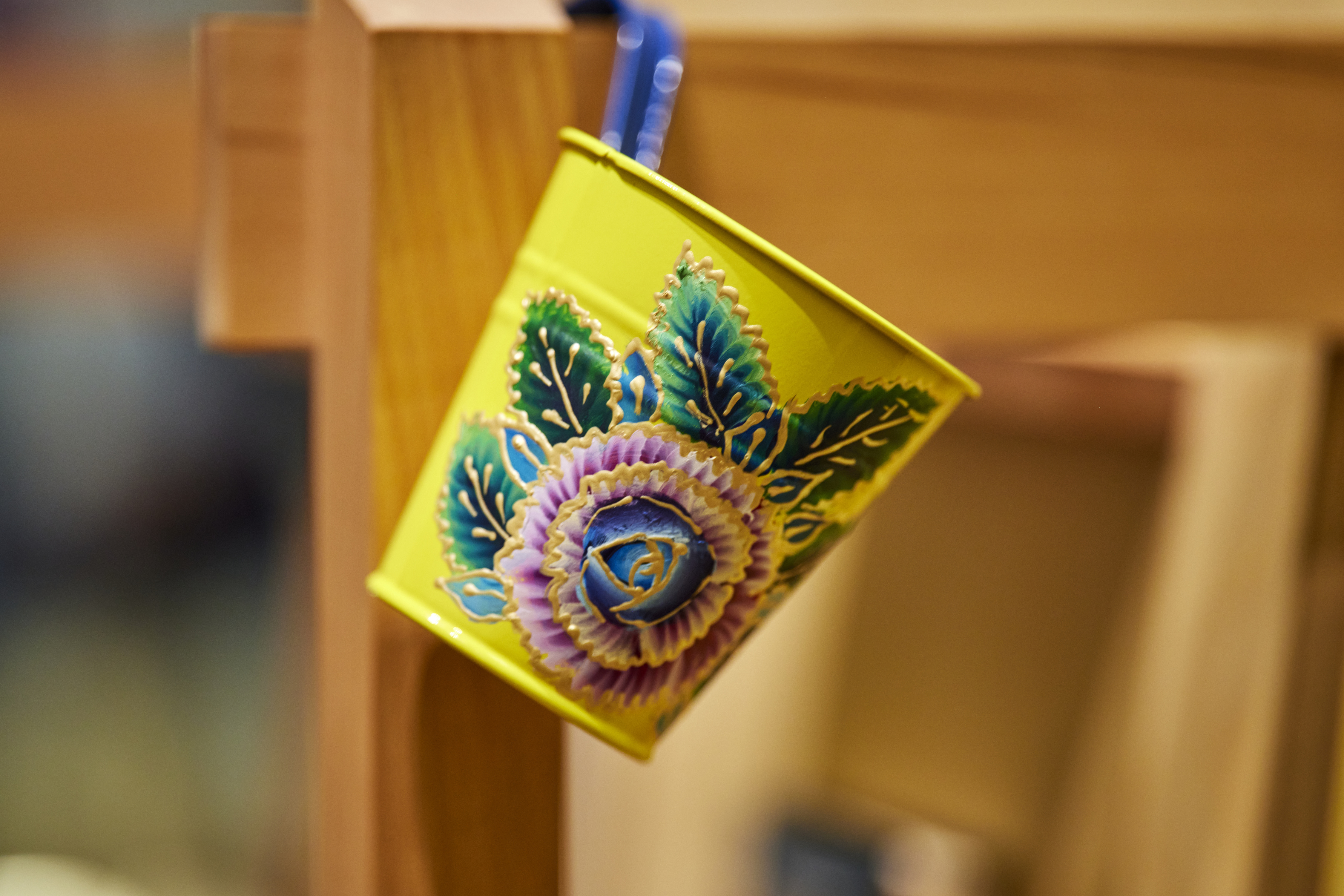 Brightly painted yellow tin pot with a colourful flower painted on it