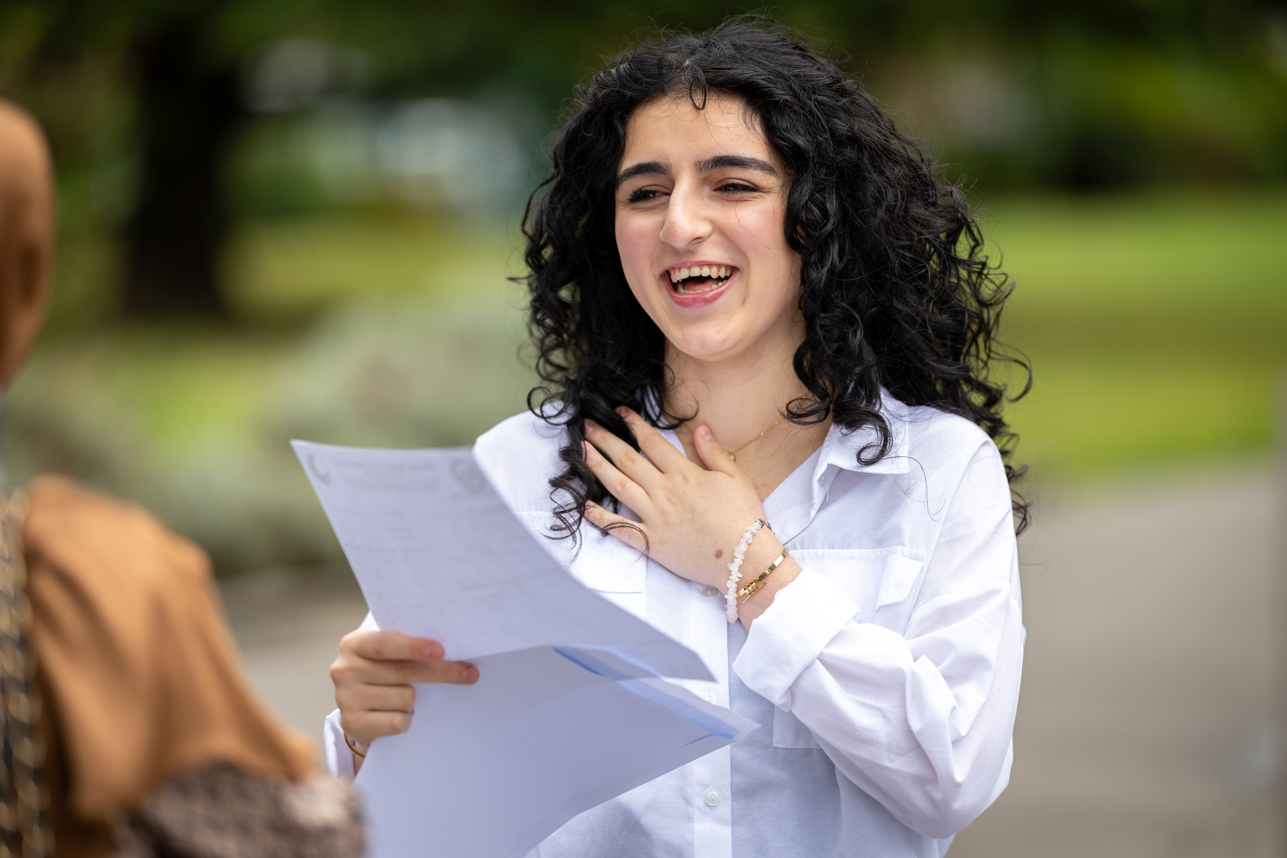 Teenage girl smiling as she looks at a piece of paper she is holding in her hands Teenage girl smiling as she looks at a piece of paper she is holding in her hands
