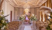 Image shows the interior of Manchester Hall set up for a wedding, with rows of seating and lots of flowers.