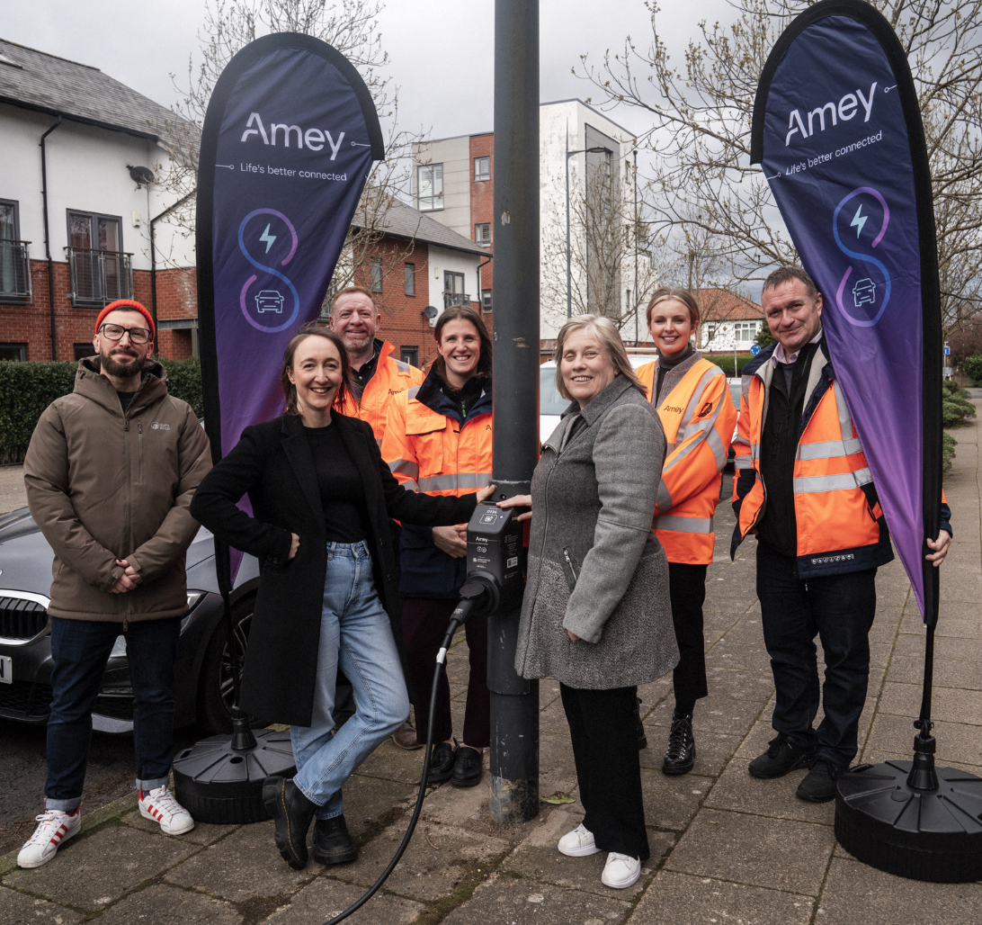 Image of a group of people around a lamppost charging station