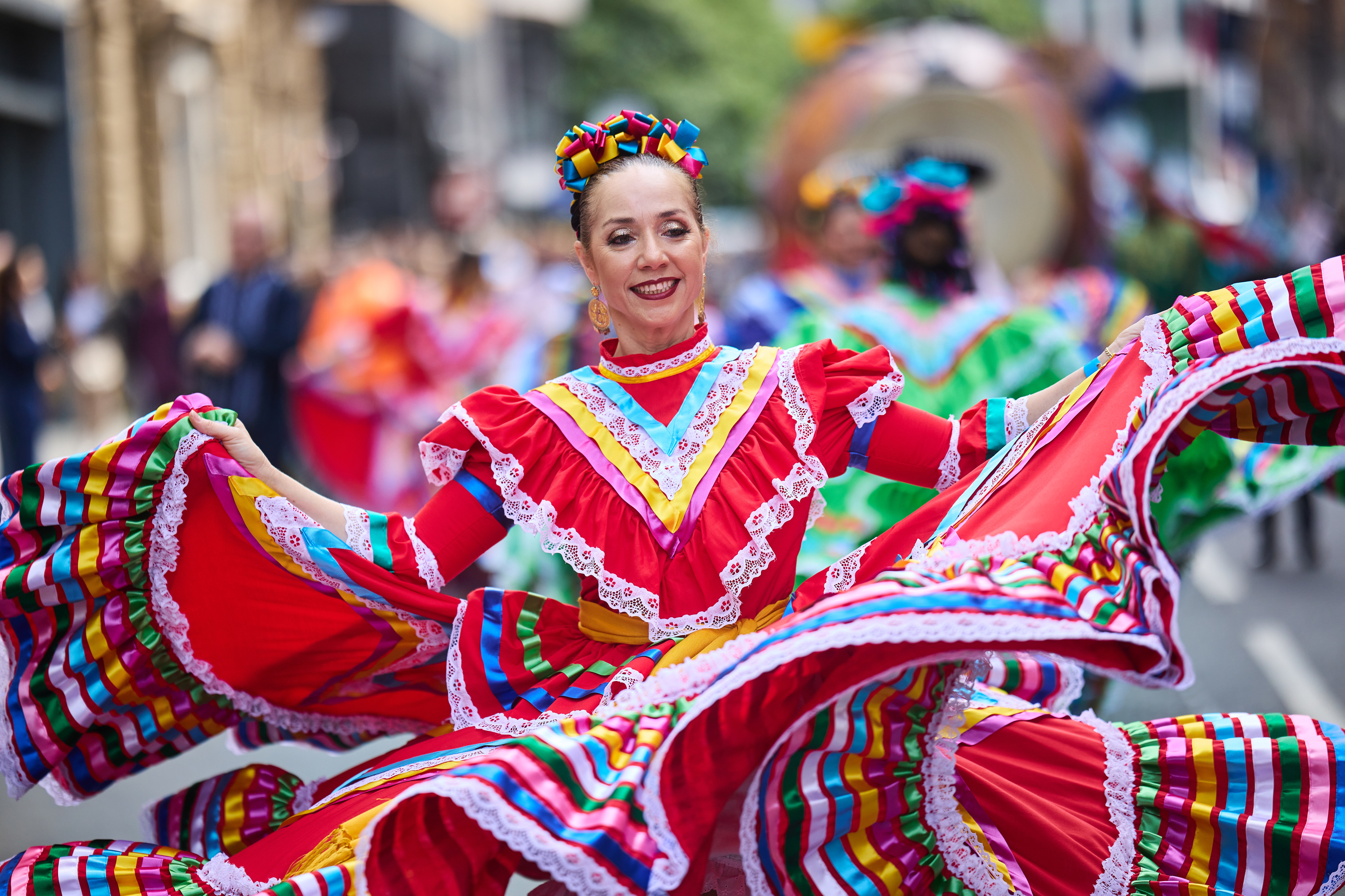 Woman dancing in the street, smiling, wearing a brightly red traditional Mexican dress  