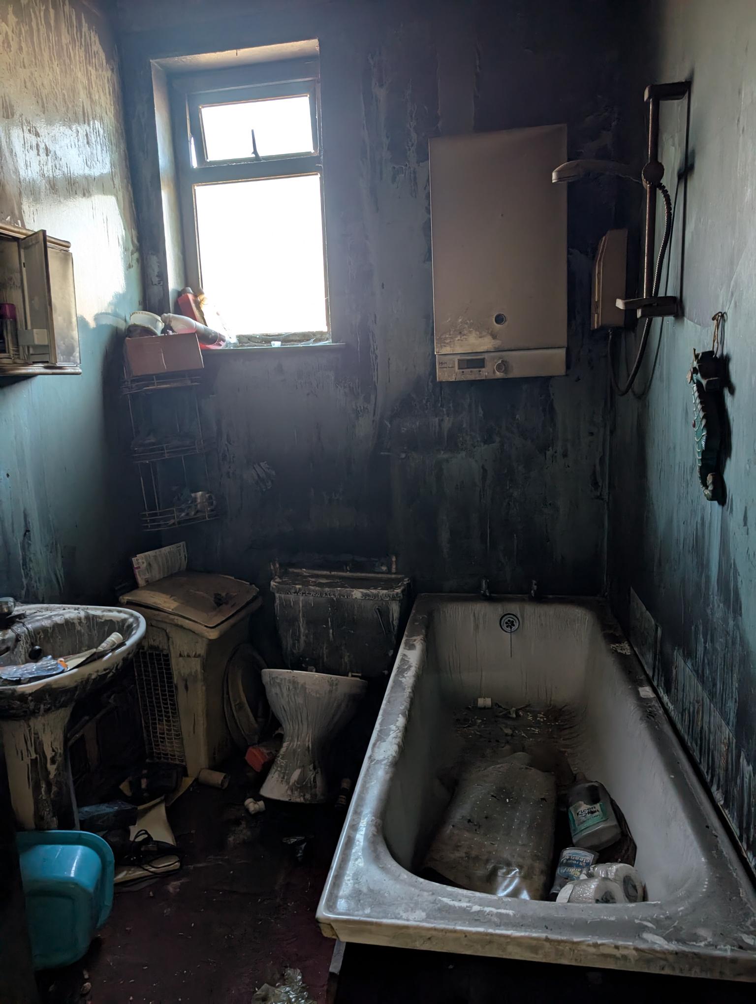 Image of a very dirty bathroom caused by fire with black walls and dirty surfaces